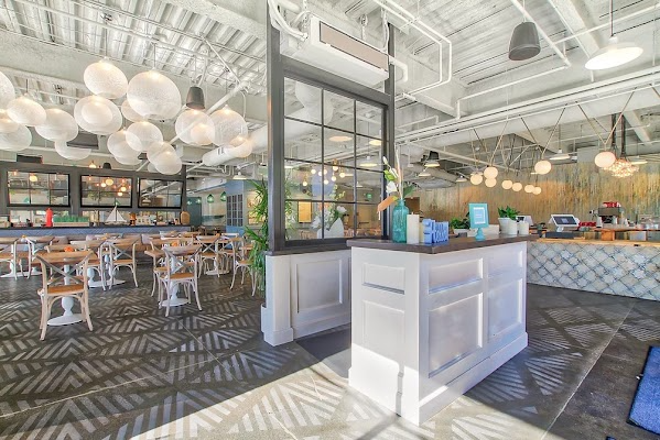 Bright modern restaurant interior with white booth seating, pendant lights, and a tiled service counter