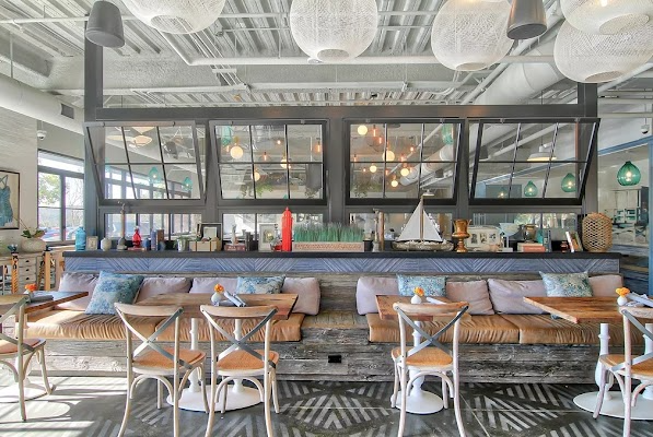 Bright modern restaurant bar with wood tables, blue stools, and hanging globe lights