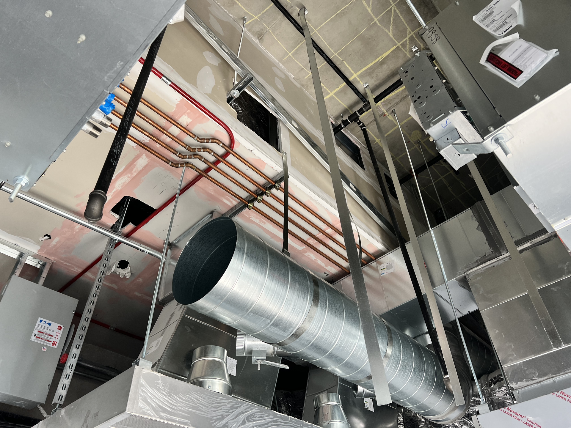 Ceiling ductwork and red fire sprinkler pipes in an unfinished industrial interior