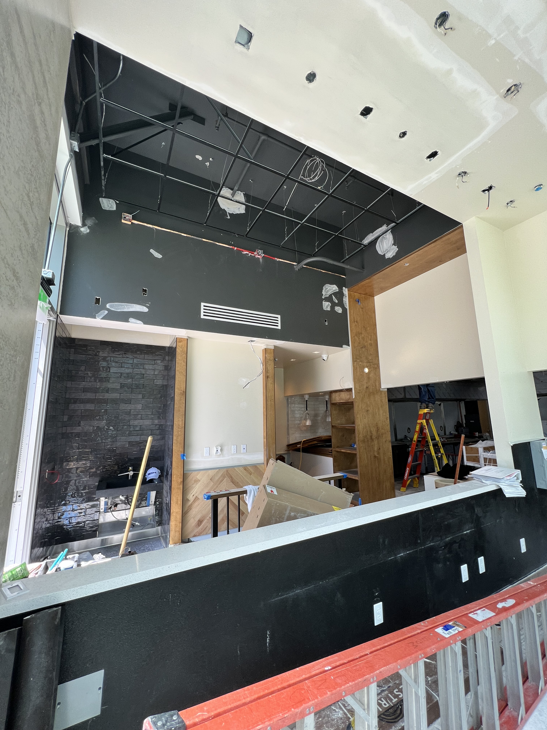 Interior construction site with black walls, white ceiling, tools, and unfinished counters