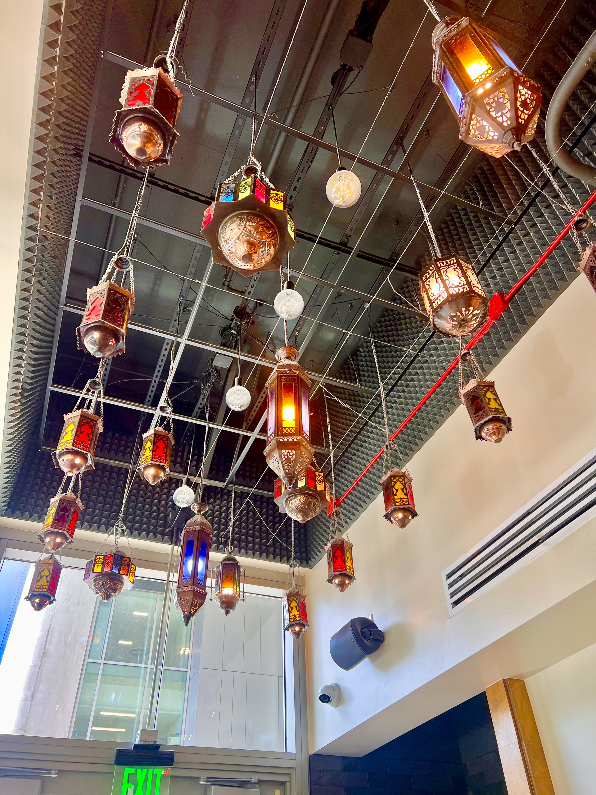 Hanging glass lanterns and string lights on a ceiling in a bright indoor space