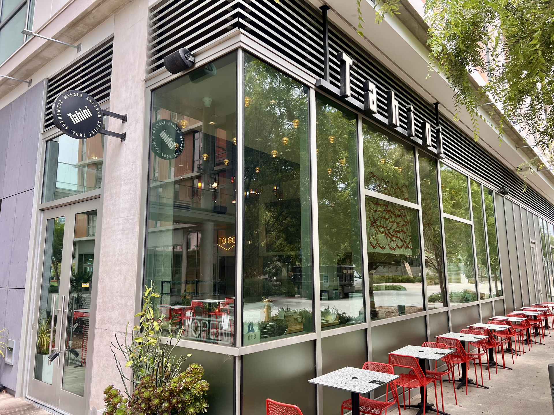 Corner cafe with large glass windows and outdoor seating along the sidewalk