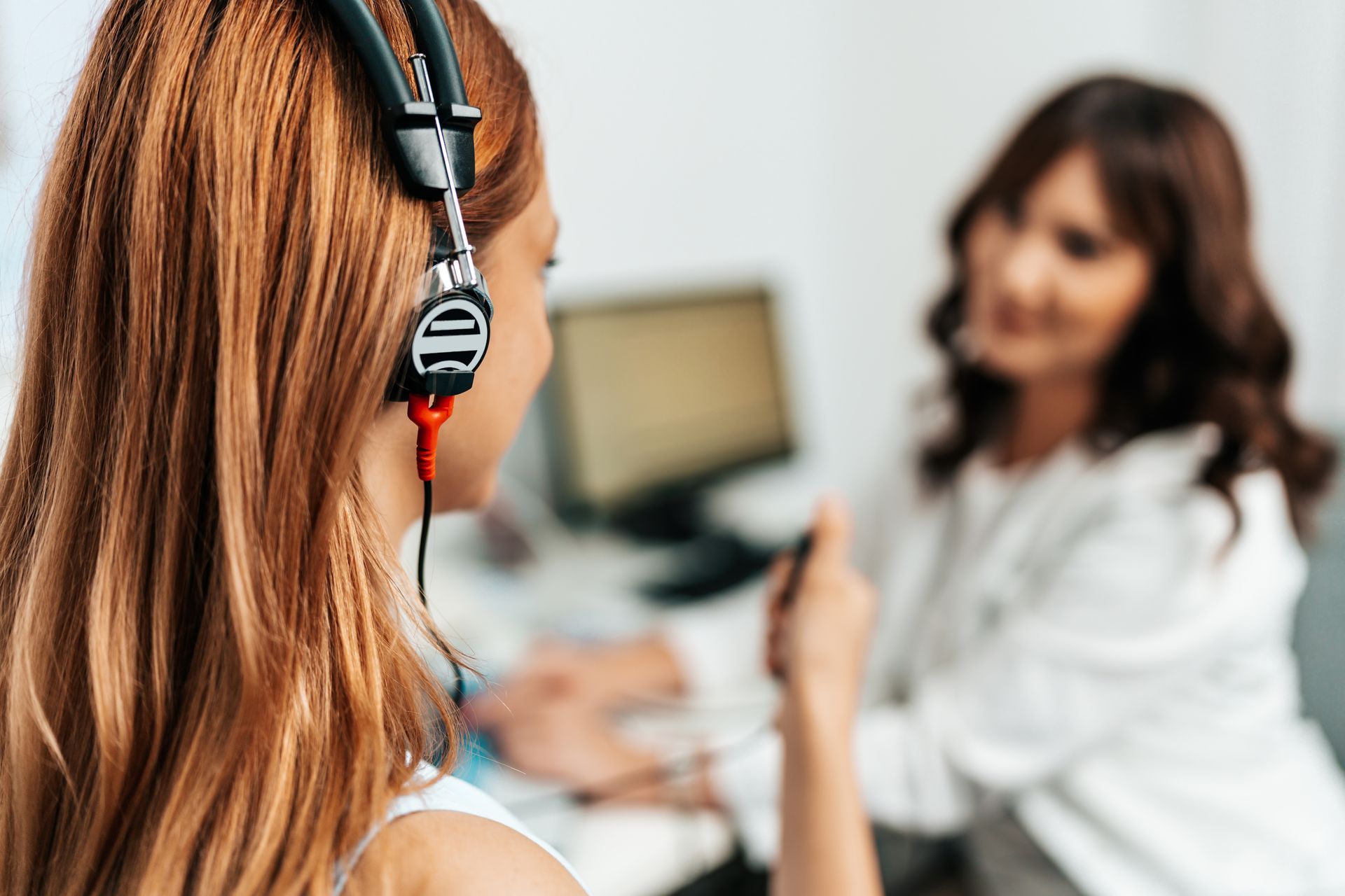 A woman wearing headphones is talking to a doctor.