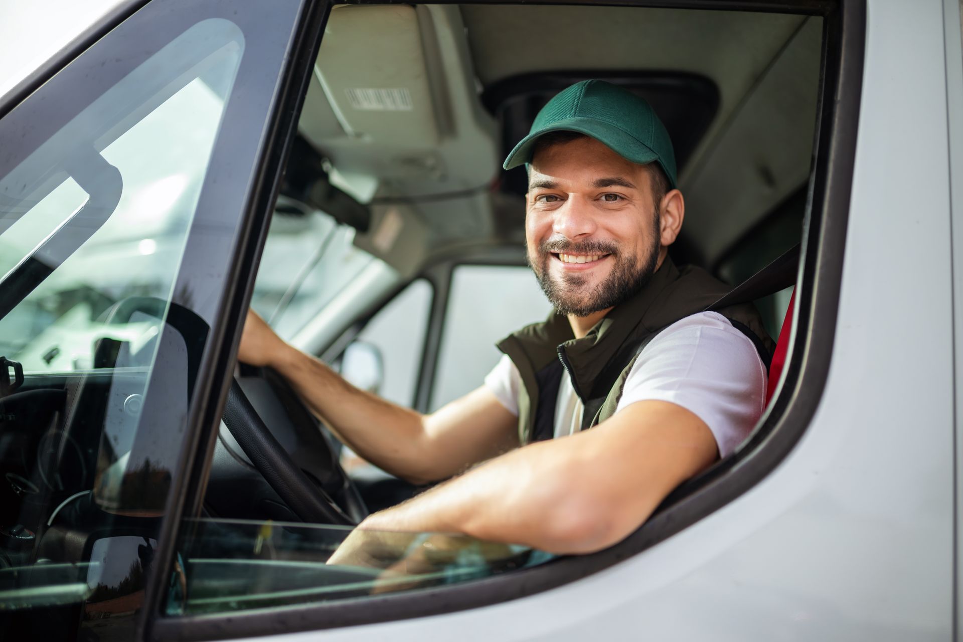 A man is sitting in the driver 's seat of a van and smiling.