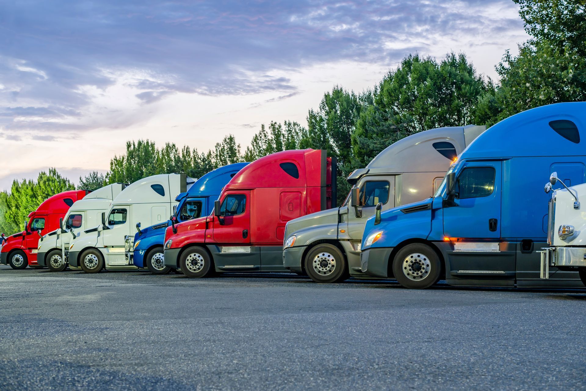A row of semi trucks are parked in a parking lot.
