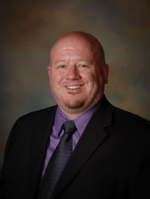 A man in a suit and tie is smiling for the camera