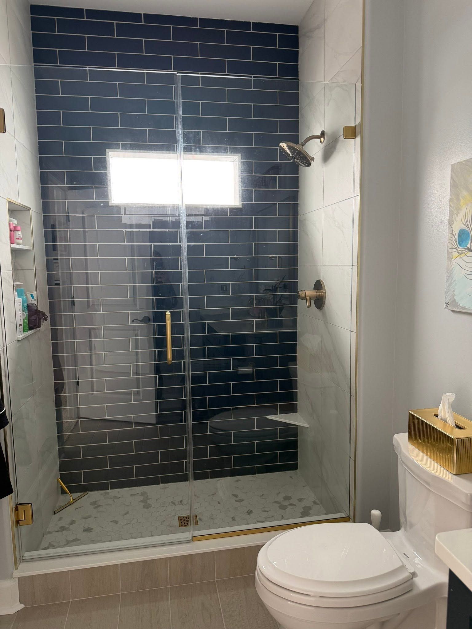 Modern bathroom with a glass shower enclosure, dark tile, and a white toilet.