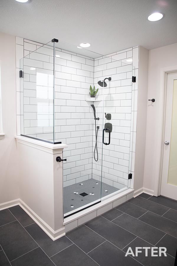 New white-tiled shower with glass enclosure and dark gray floor tiles in a bathroom
