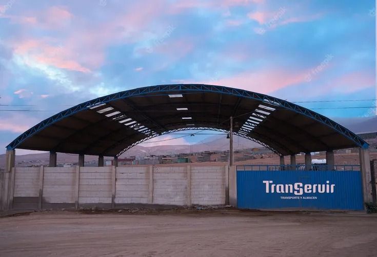 Gran estructura metálica arqueada al anochecer con un letrero azul de Trongeur a la derecha.