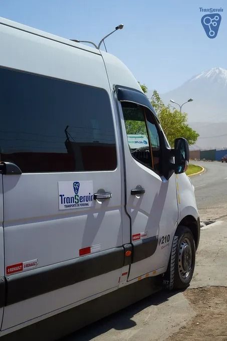 Furgoneta de reparto blanca aparcada junto a una carretera con montañas al fondo.