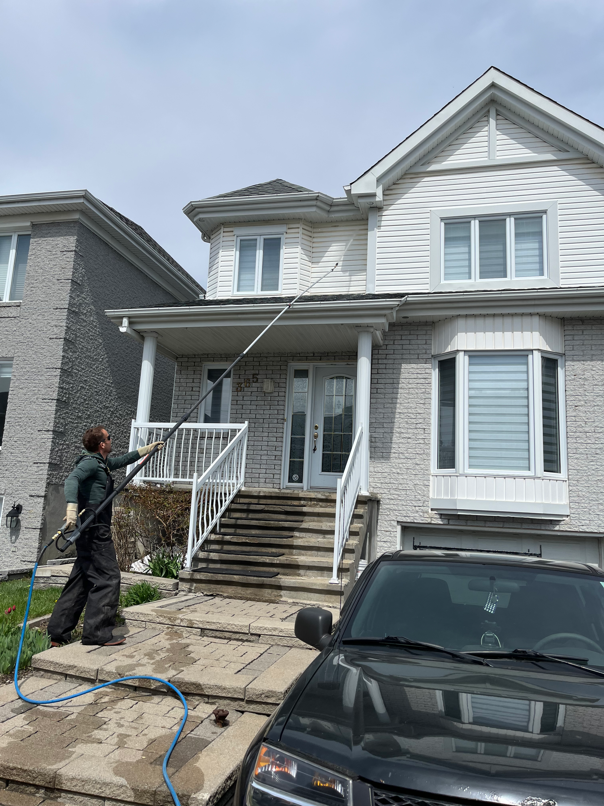 Un homme nettoie le côté d'un bâtiment en briques avec un tuyau.