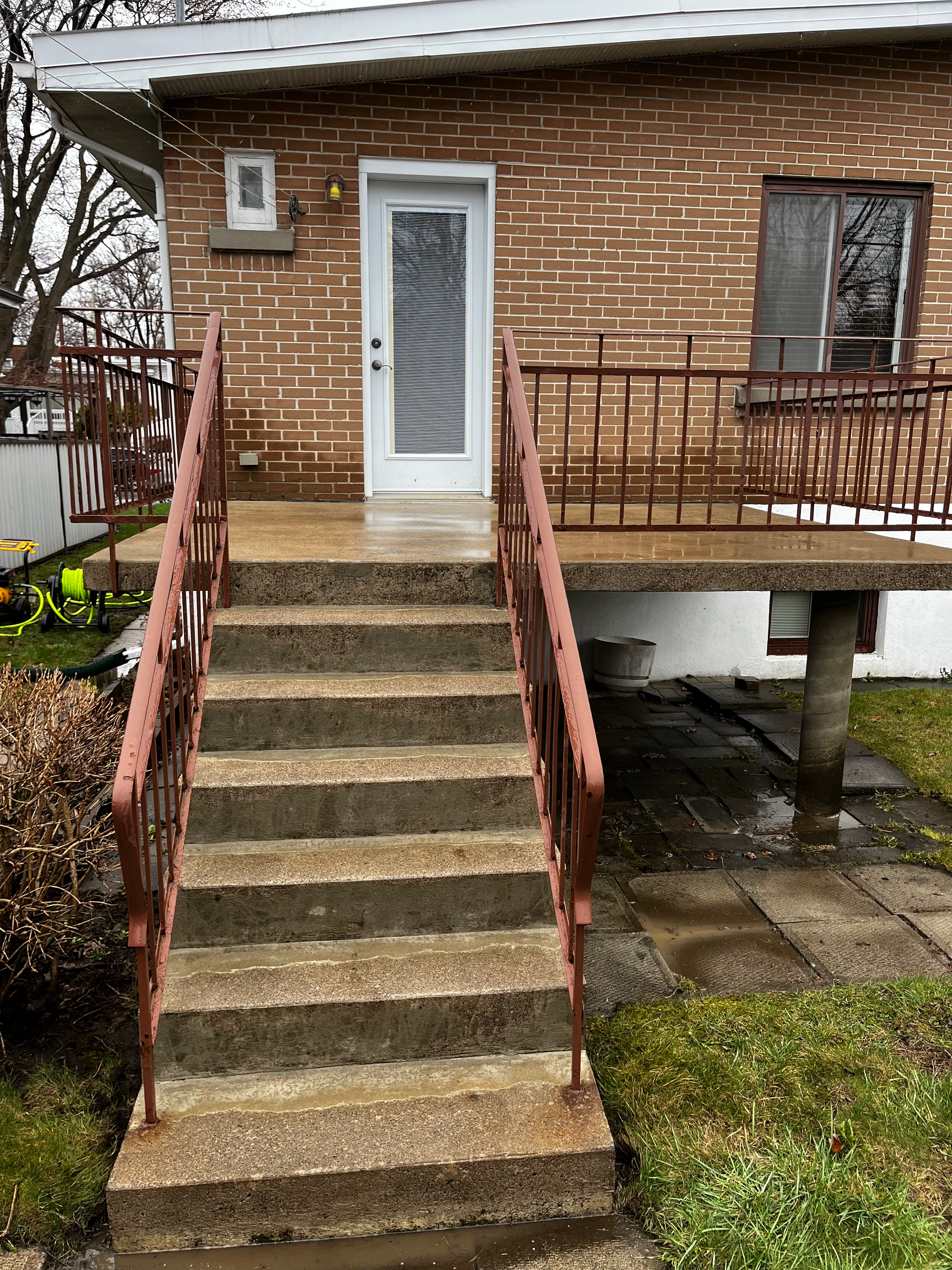 A brick house with stairs leading up to the front door and a balcony.