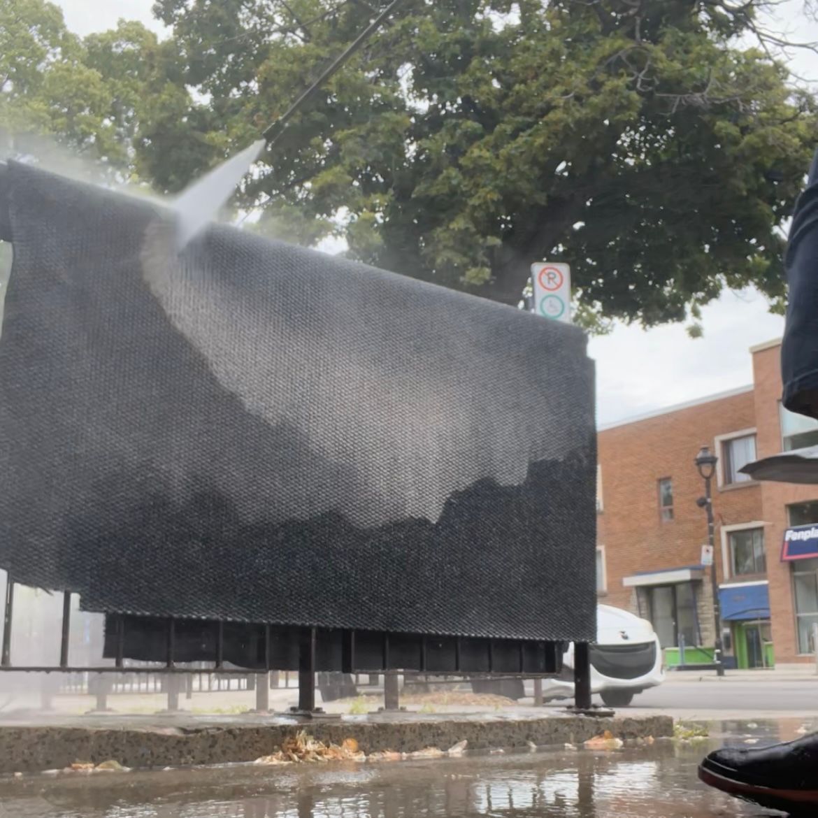 A person is cleaning a billboard with a high pressure washer