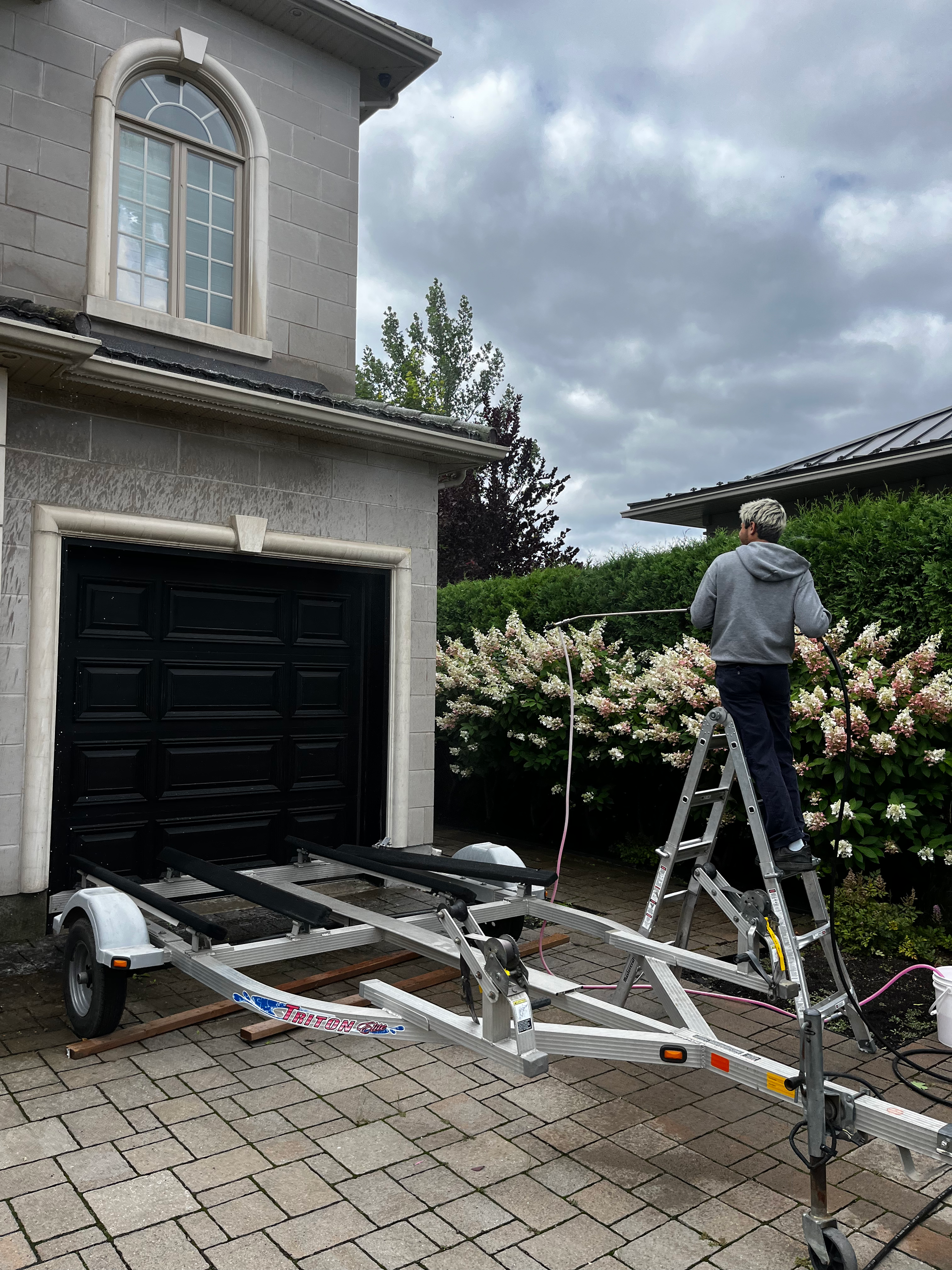 Un homme nettoie le toit d'une maison en briques avec un nettoyeur haute pression.