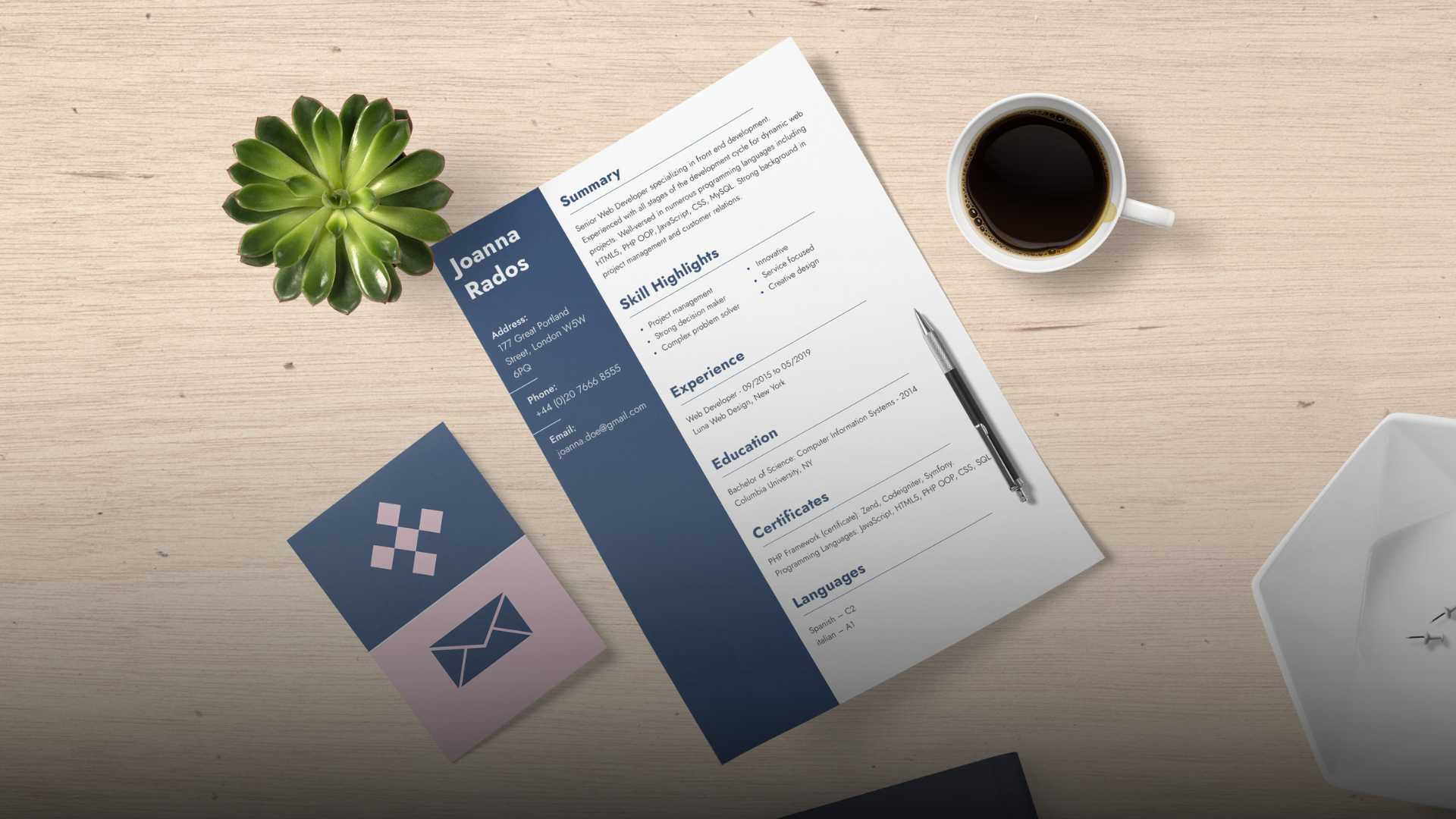 Resume on a desk with a coffee cup, pen, plant, and business card.