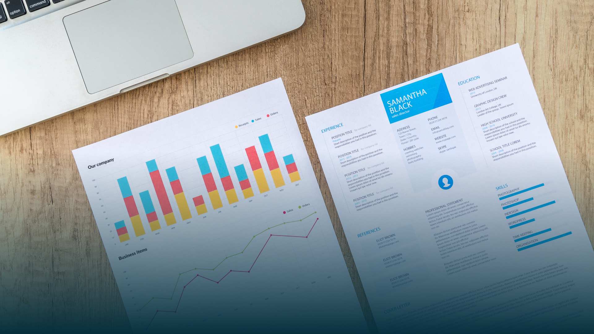 Laptop next to two documents with charts and data on a wooden surface.