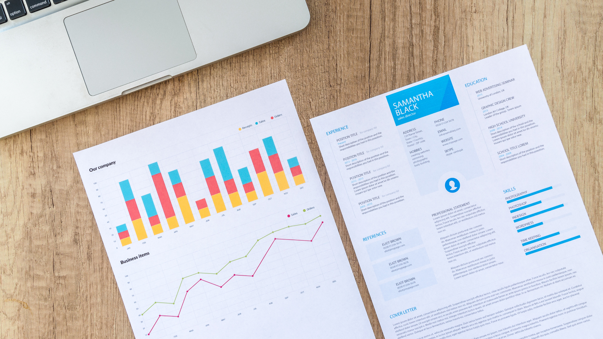 Laptop, charts and graphs on documents arranged on a wooden table, possibly a financial analysis.