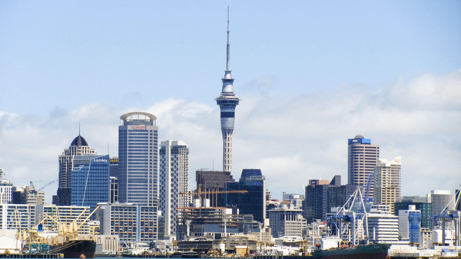 Auckland, New Zealand skyline with the Sky Tower prominent in the center, sunny day.
