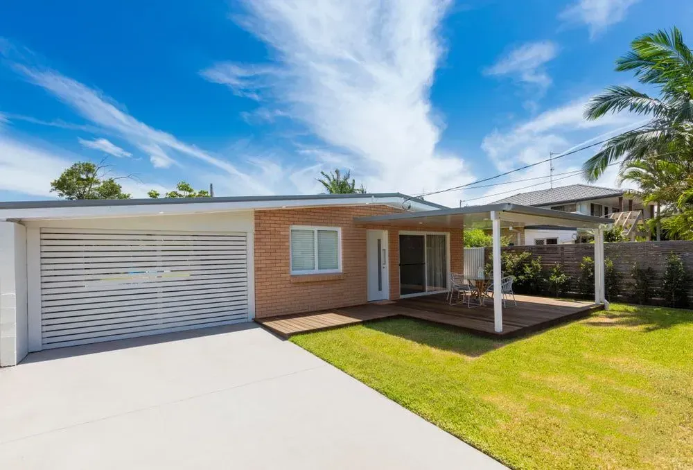 Brick Home With Garage, Wooden Deck, Green Lawn, and Blue Sky — All Around Concreting in Casino, NSW
