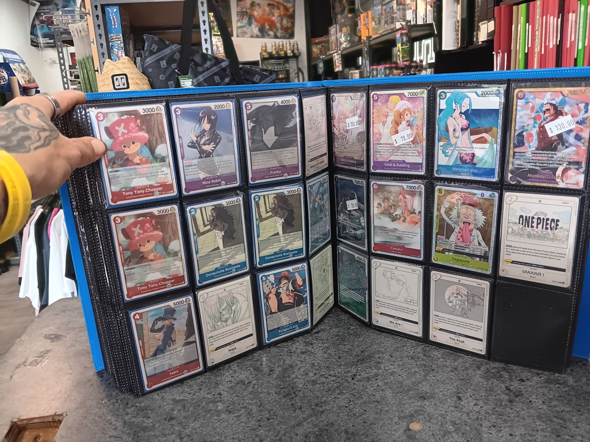 A Person Holding a Binder of Trading Cards in a Store — Grim Gaming & Hobbies in Bundaberg Central, QLD