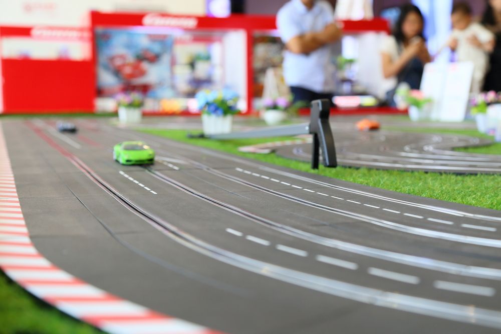 Green Toy Car Racing on a Miniature Track With Spectators in the Background — Grim Gaming & Hobbies in Bundaberg Central, QLD