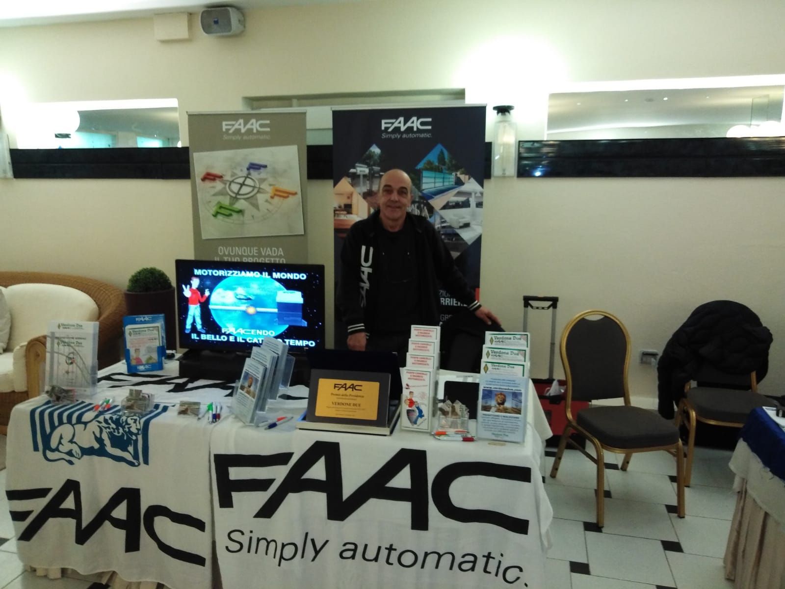 Un uomo è in piedi dietro un tavolo su cui è scritto FAAC Simply Automatic