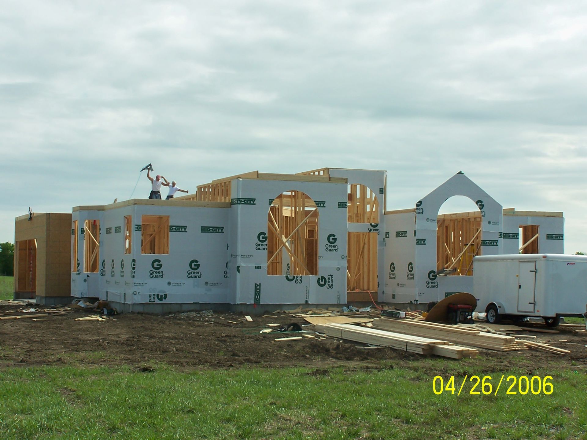 Partially built house with exposed framing and plywood walls on a muddy construction site