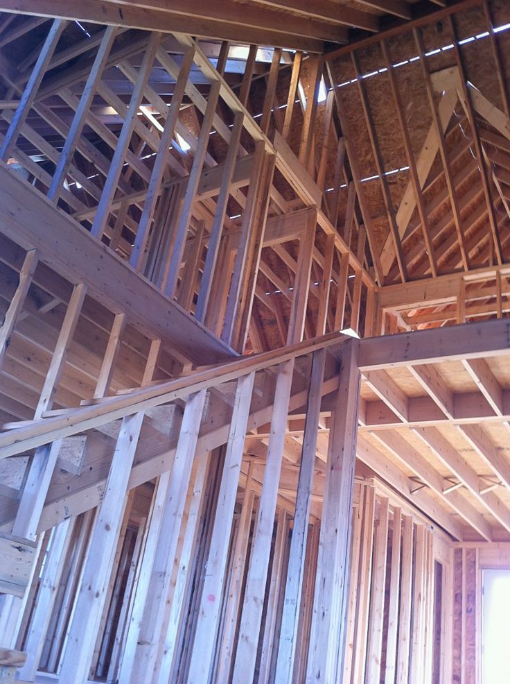 Interior wooden house framing with exposed beams and trusses under construction