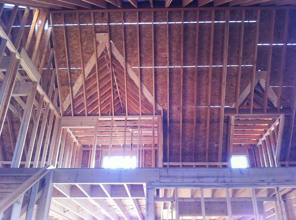 Exposed wooden roof trusses and beams inside an unfinished attic or loft space