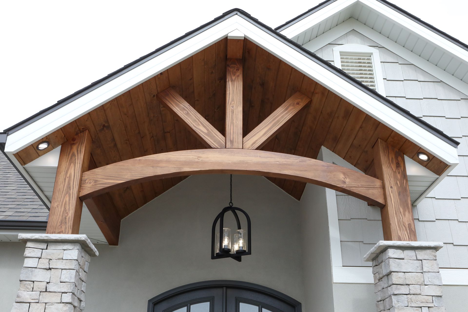 Wooden gabled porch roof with exposed beams and a hanging lantern above a house entry