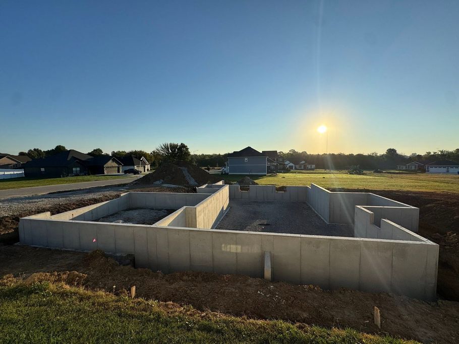 Concrete foundation of a house under construction at sunset in a rural field