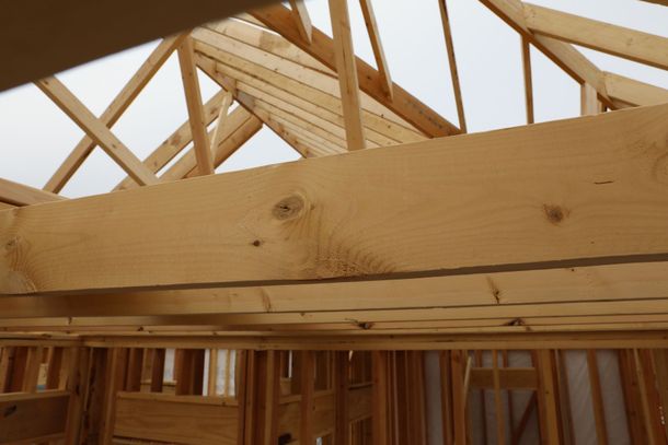 Wooden roof trusses and beams framing the interior of a house under construction
