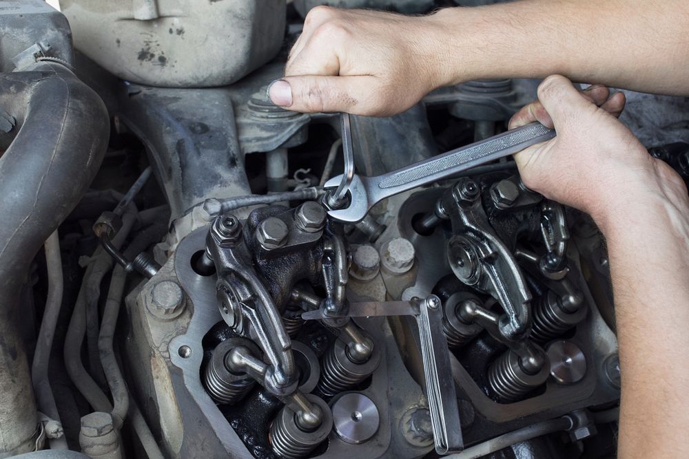 Hands using a wrench to adjust motorcycle engine parts under the seat — Bundaberg Field Service in Bargara, QLD