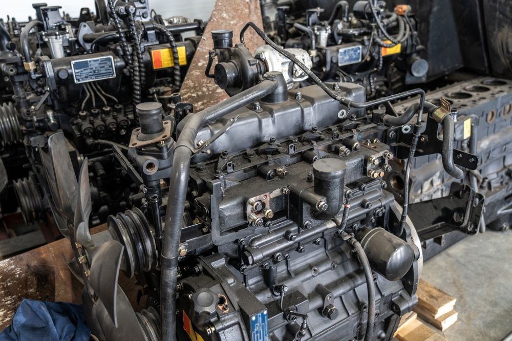 Stacked used engines and machinery parts in a workshop, mostly black metal with gray components. — Bundaberg Field Service in Childers, QLD