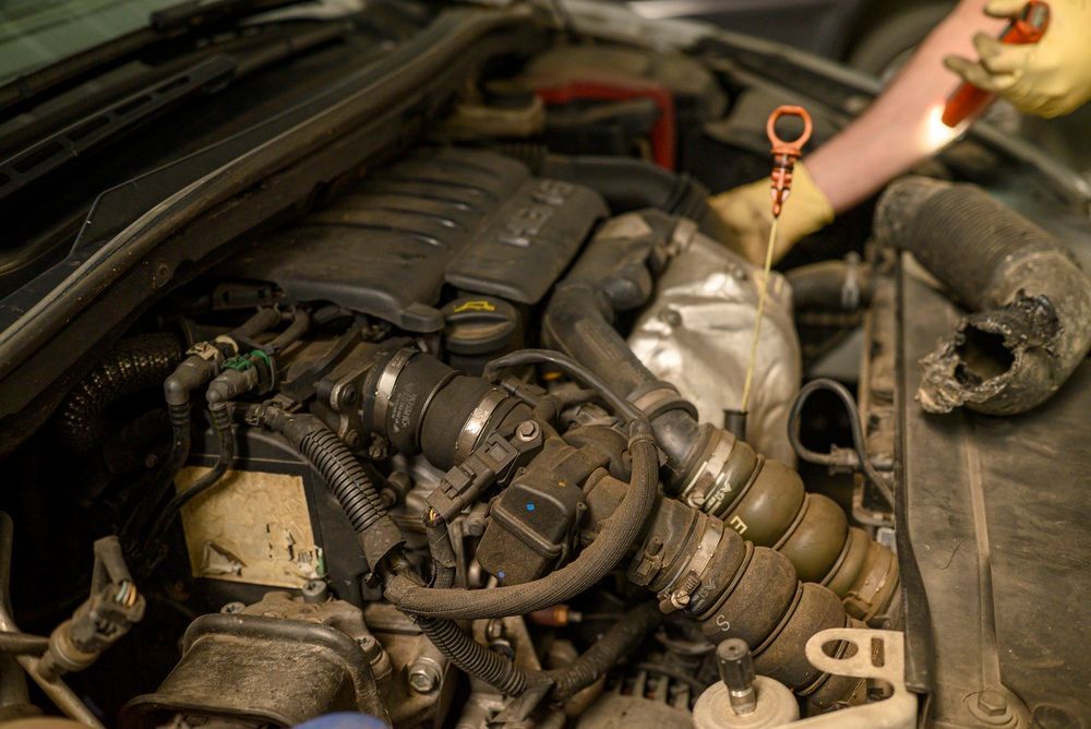 Car engine bay with a mechanic’s hand checking the oil dipstick near the engine. — Bundaberg Field Service in Bundaberg East, QLD