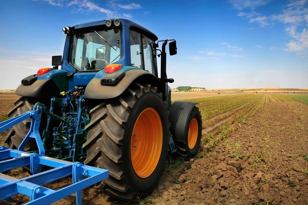 Large tractor plowing a field under a blue sky — Bundaberg Field Service in Bundaberg East, QLD