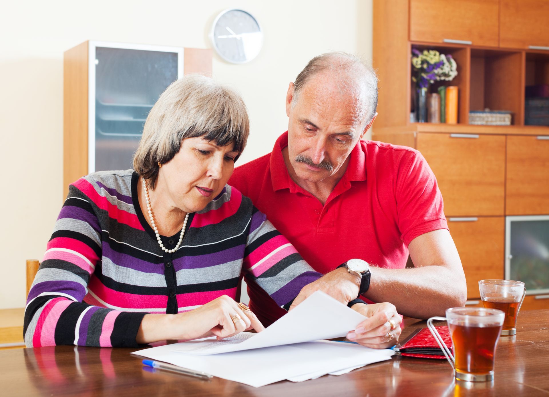 Older couple reviewing financial documents together at home.