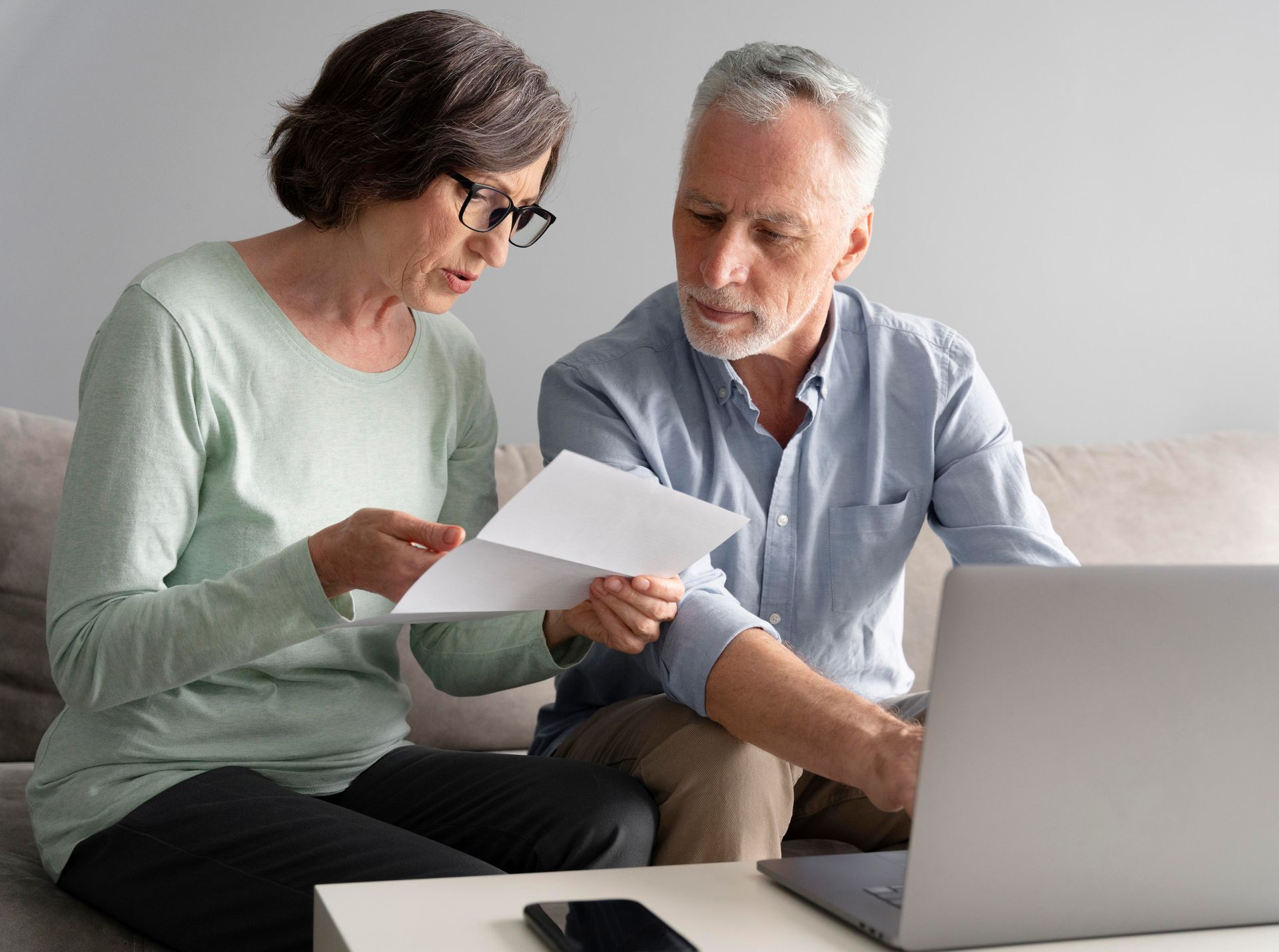 Retired couple comparing pension drawdown and annuity income options at home.