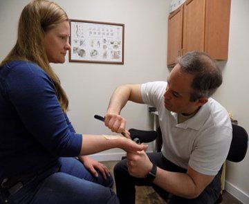 Clinician examining a patient’s forearm in a medical exam room
