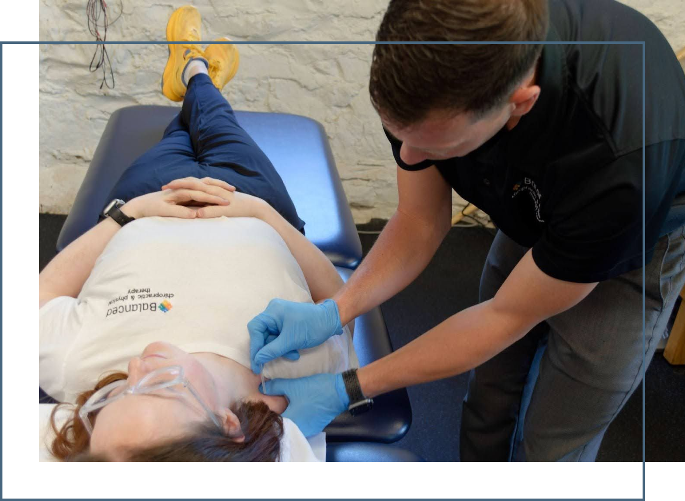 Therapist applying treatment to a patient lying on a blue table in a clinic