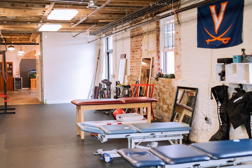 Spacious studio with tables, stacked frames, chairs, and a white projection screen on the back wall