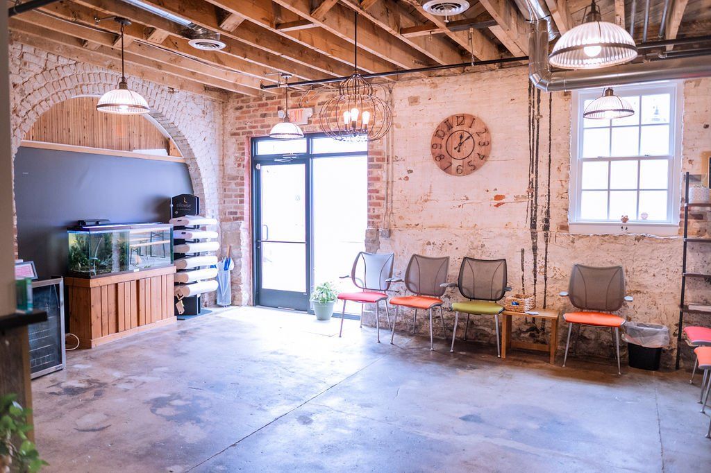Rustic room with exposed wood beams, brick walls, windows, and chairs along the wall