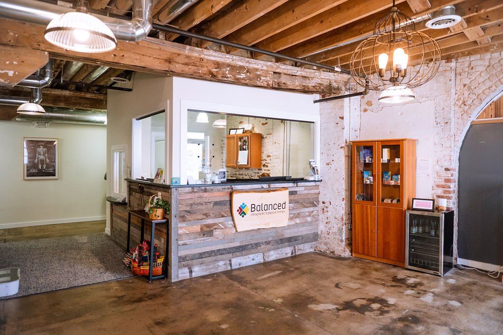 Rustic lobby with exposed beams, reception window, wooden door, and concrete floor.