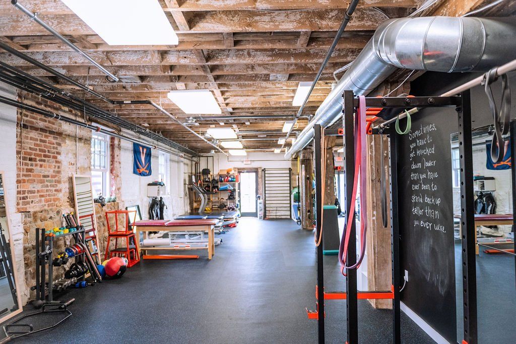 Industrial gym interior with exposed beams, workout equipment, and chalkboard wall
