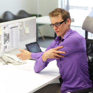 Man strectching arm at desk 