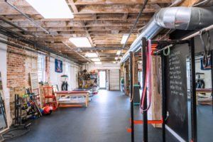 Industrial-style gym interior with equipment, brick walls, and exposed ceiling ductwork