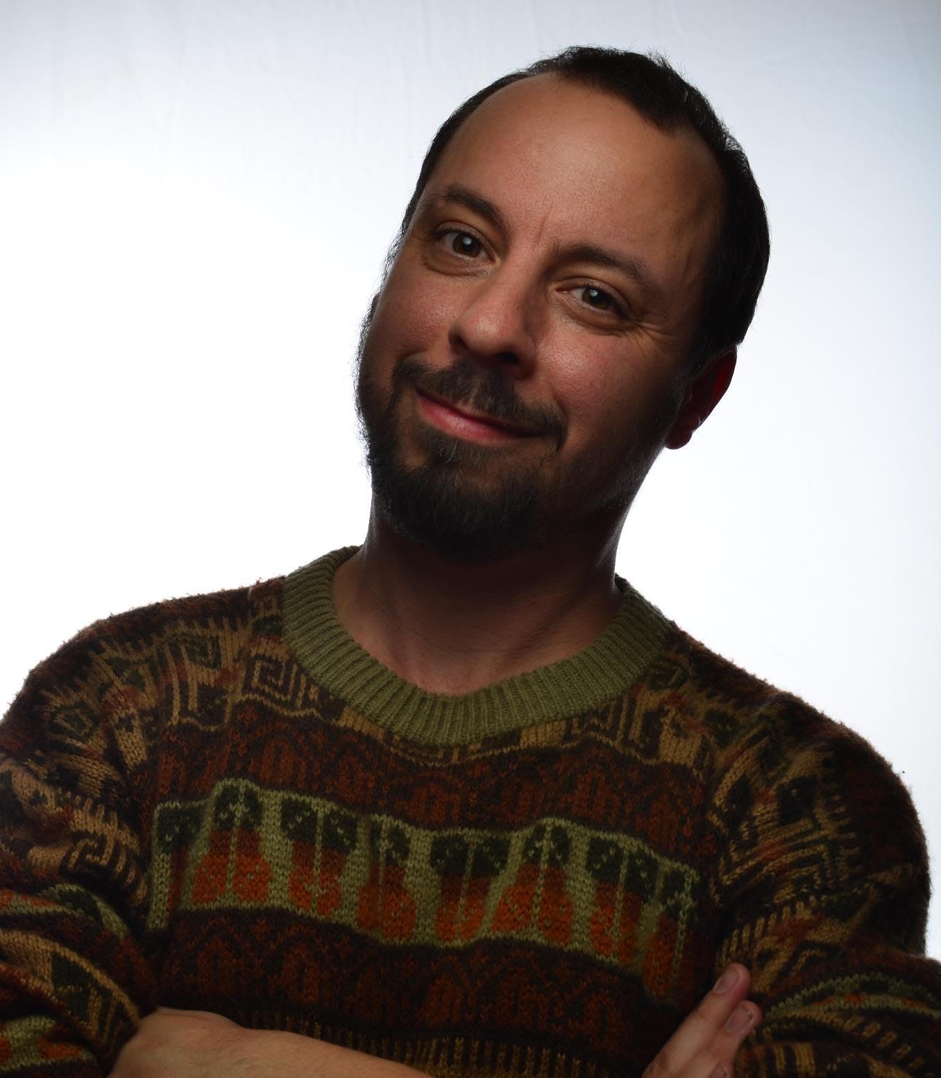Smiling man in a patterned sweater against a plain light background