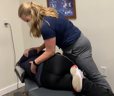 Chiropractor adjusting a patient lying face down on a treatment table in a clinic room.