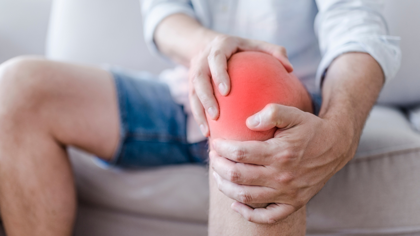 Person holding a glowing red knee while sitting on a couch