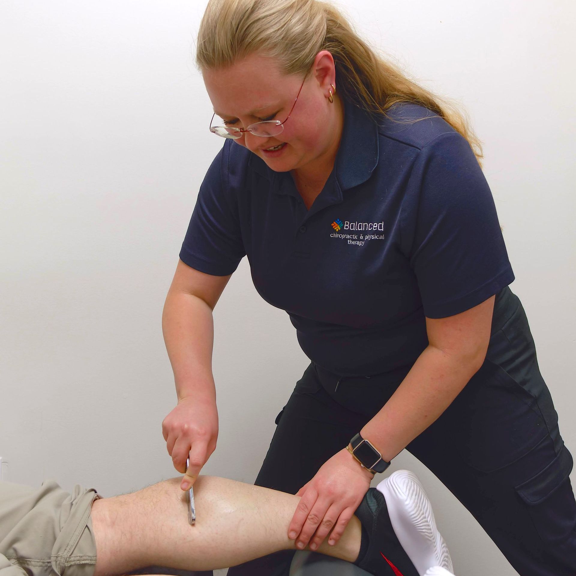 Clinician performing leg ultrasound on a patient lying on a treatment table